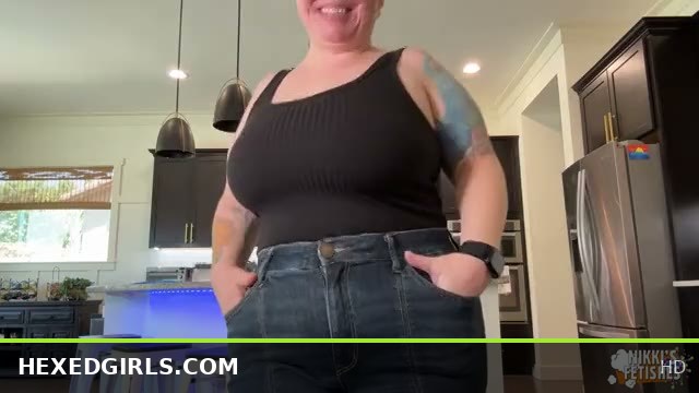 Tattooed Goth Woman in Jeans Bends Over Counter and Strikes a Pose on Stool